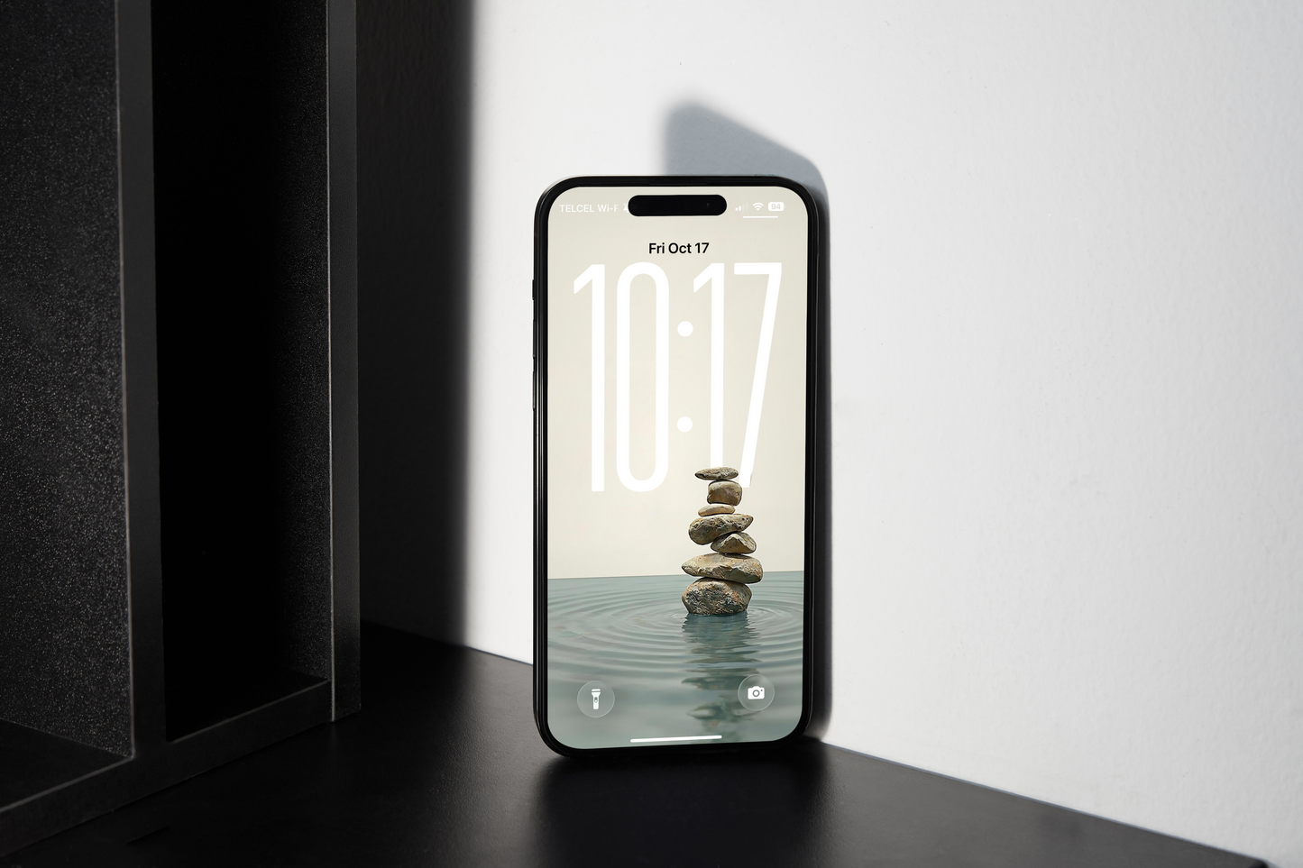 Smartphone displaying a screen with stones in water on a black surface.