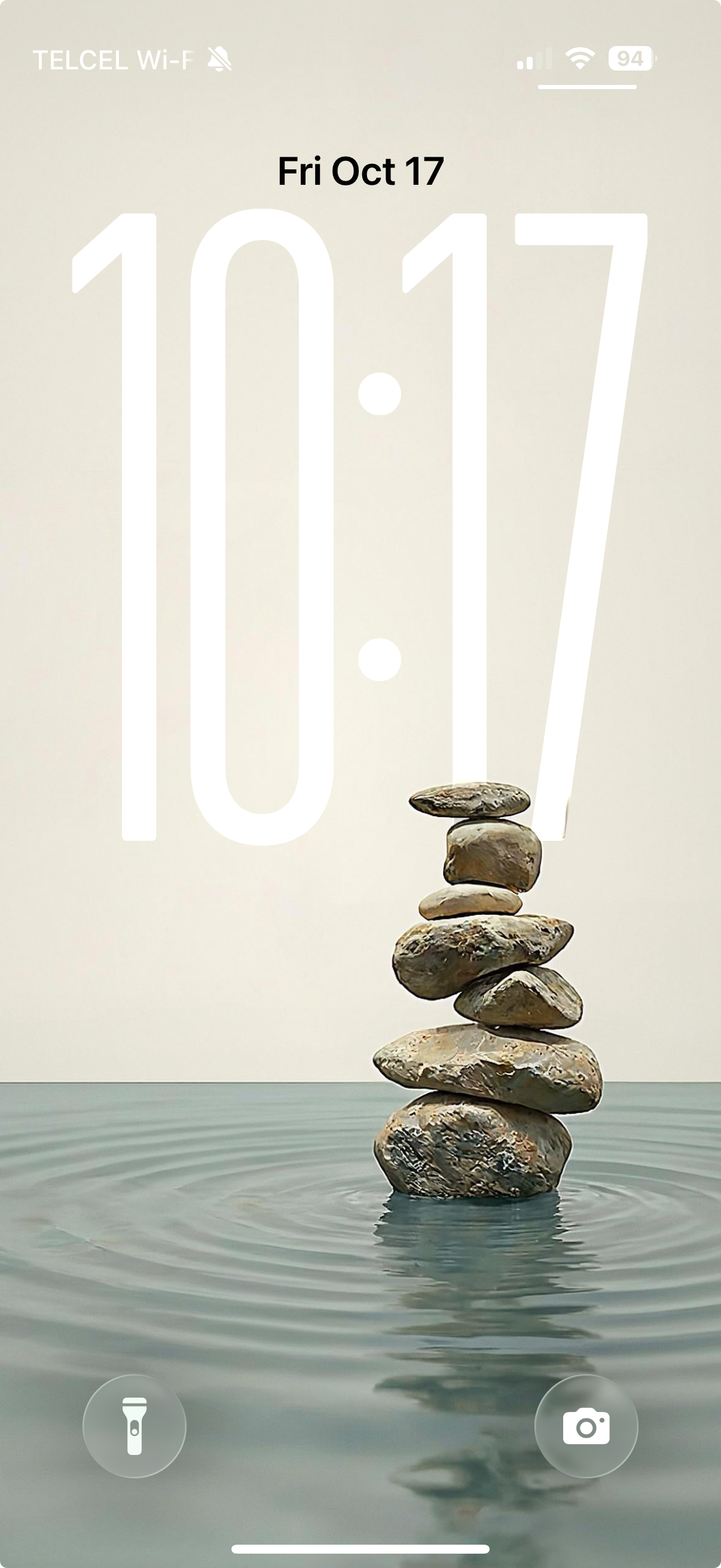 Phone screen showing the time '10:17' with a stack of stones on water.